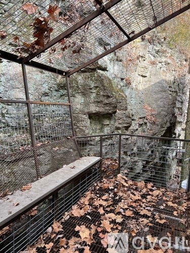 A metal fence encloses a rocky area with a bench.