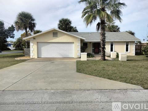 A house with a garage and a palm tree in front.
