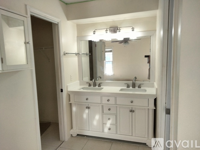 A bathroom with a white vanity and a mirror above it.