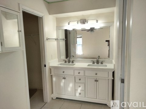 A bathroom with a white vanity and a mirror above it.