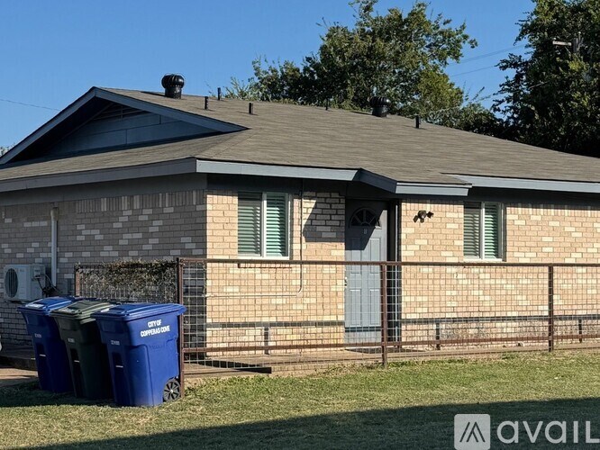 A house with a blue recycling bin in front of it.