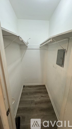 A hallway with a white wall and a wooden floor.