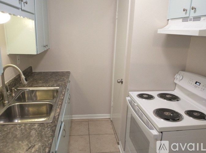 A kitchen with a stove, sink, and cabinets.