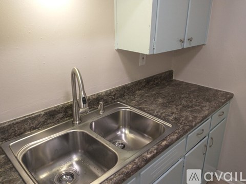 A kitchen sink with a faucet and a granite countertop.