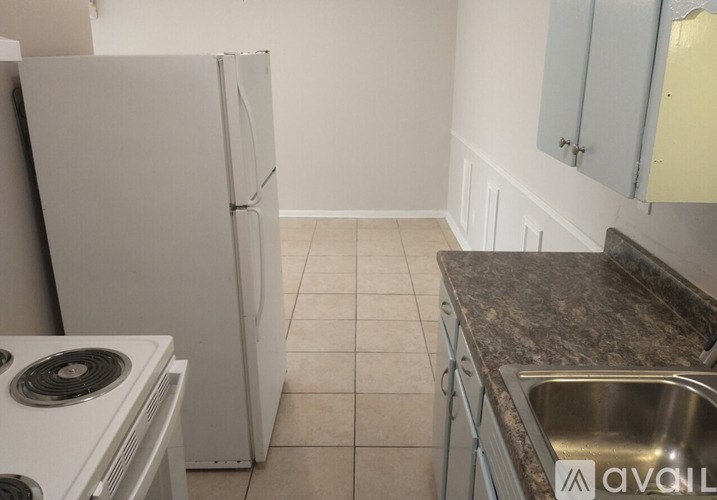 A kitchen with a white fridge, stove, and sink.