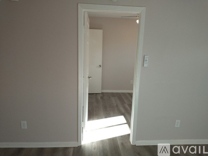 A white door is open to a room with wooden flooring.