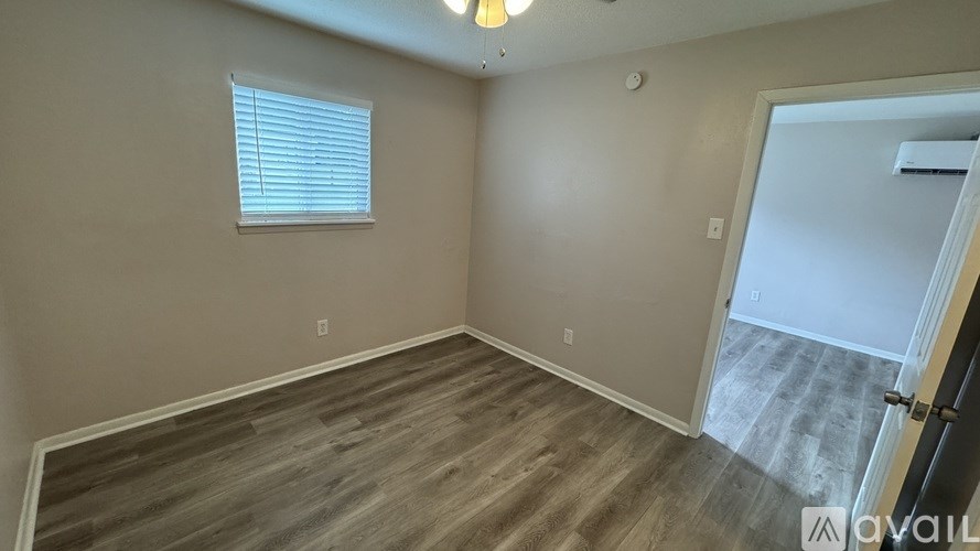 A room with wooden flooring and a window with blinds.
