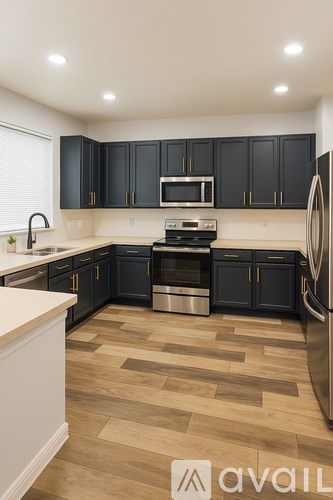 A kitchen with black cabinets and a wooden floor.