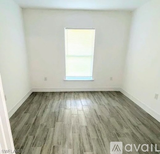 A room with a window and wooden flooring.