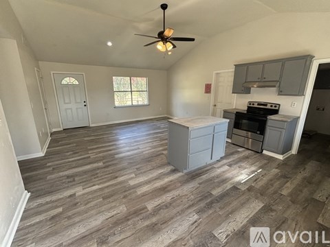 A kitchen with a fan and wooden flooring.