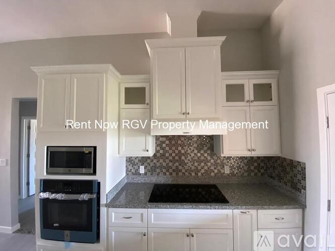 A kitchen with white cabinets and a black oven is for rent.