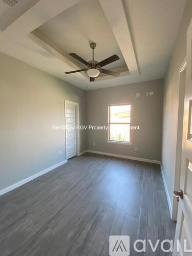 A room with a ceiling fan and a window letting in light.