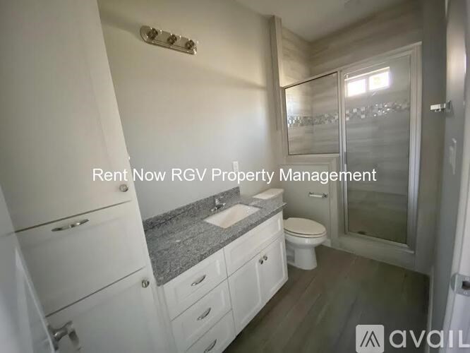 A bathroom with a toilet, sink, and cabinets is available for rent.