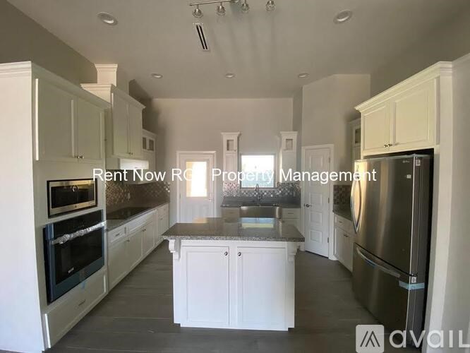 A kitchen with white cabinets and a stainless steel refrigerator is available for rent.