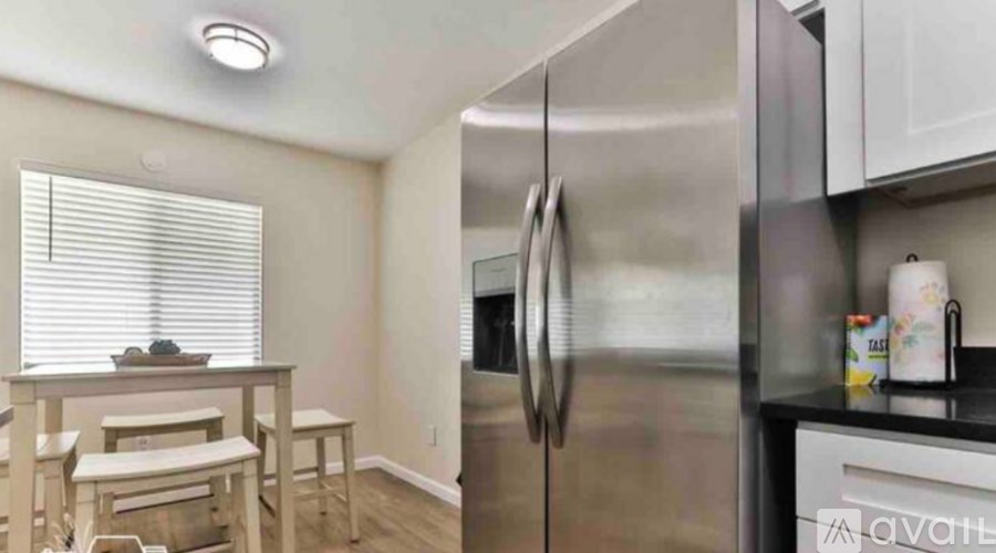 A kitchen with a stainless steel refrigerator and white cabinets.