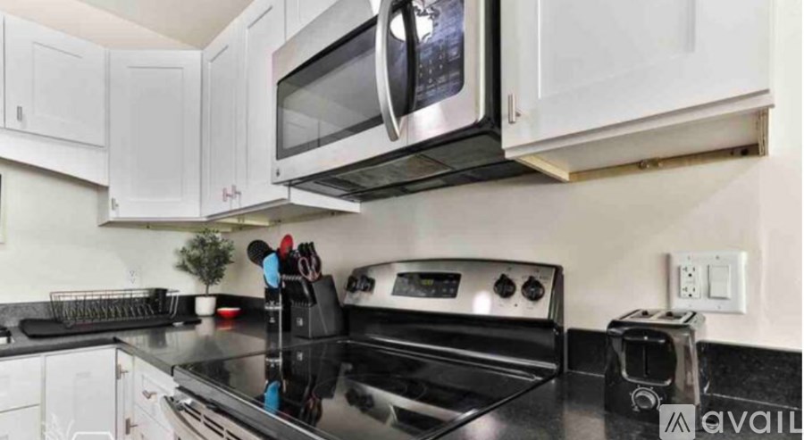 A kitchen with white cabinets and black countertops.