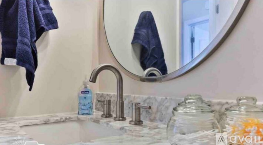 A bathroom sink with a round mirror and a blue towel hanging on the wall.
