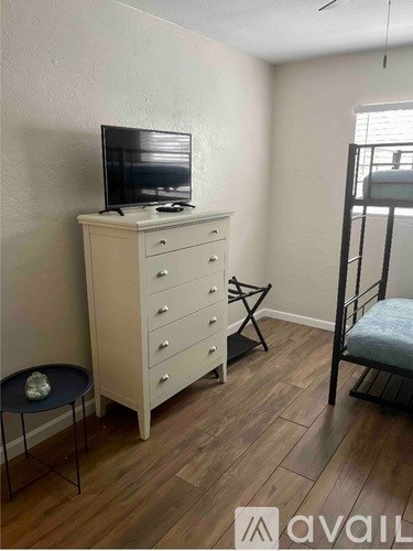 A room with a TV on top of a dresser and a chair.