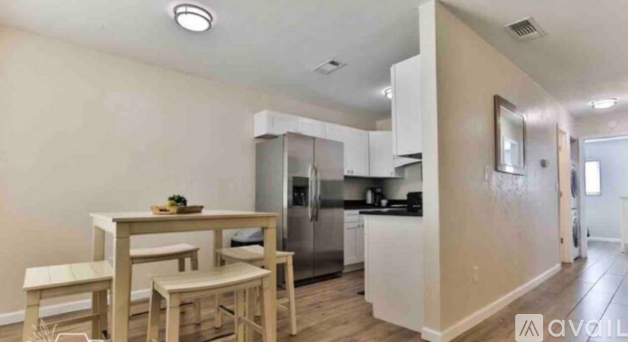 A kitchen with a table and chairs in the foreground and a refrigerator and oven in the background.