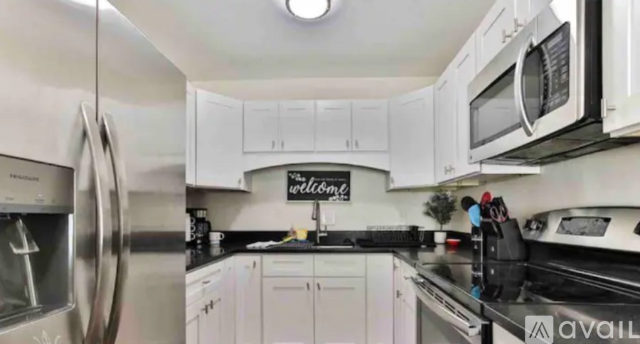 A kitchen with white cabinets and a stainless steel refrigerator.