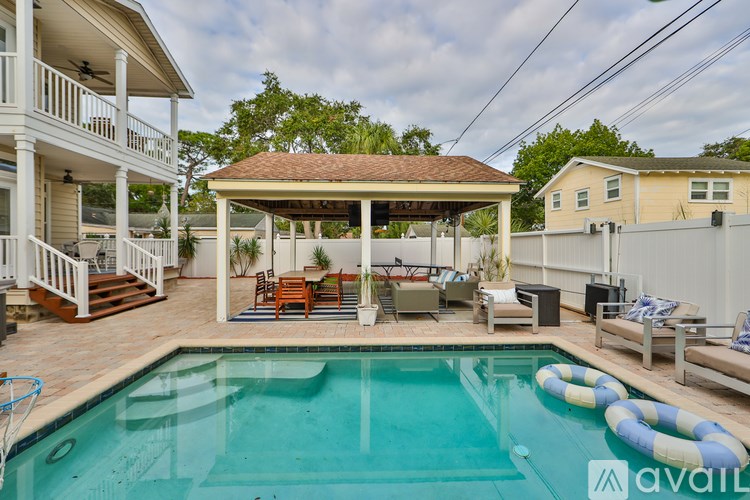 A pool with a gazebo and chairs around it.