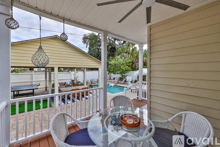 A patio with a table and chairs overlooking a pool.