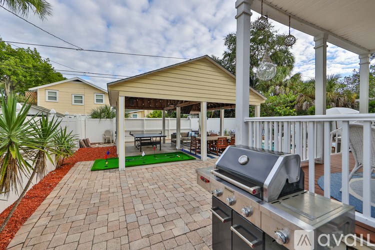 A patio with a grill and a table with chairs is surrounded by a white fence.