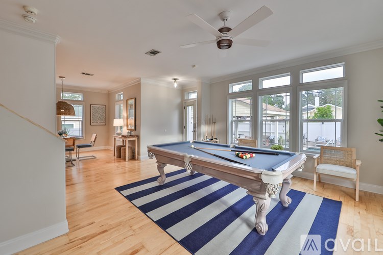 A pool table in a room with a ceiling fan and a striped rug.