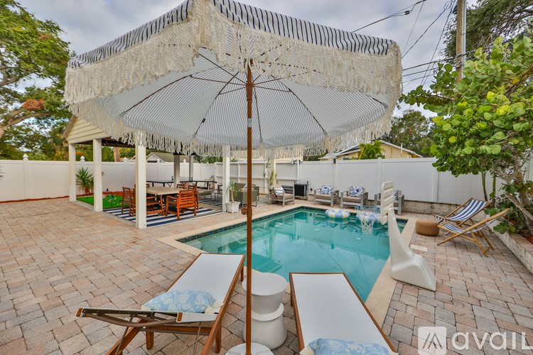 A patio with a pool and a white umbrella.