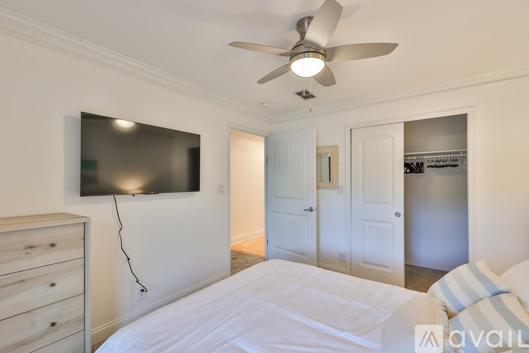 A bedroom with a bed, dresser, and a ceiling fan.