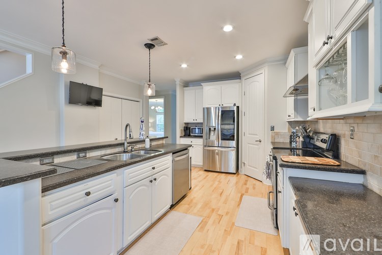 A modern kitchen with white cabinets and stainless steel appliances.