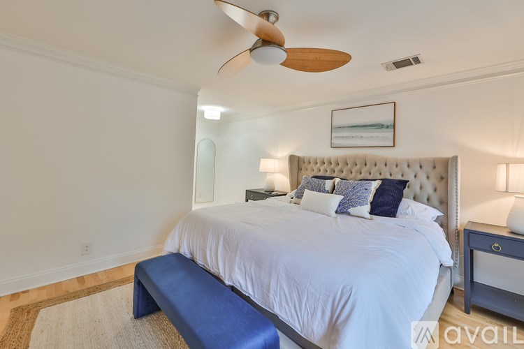 A bedroom with a large bed, a ceiling fan, and a bench.