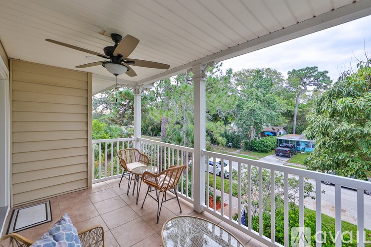 A balcony with a fan and chairs overlooking a street.