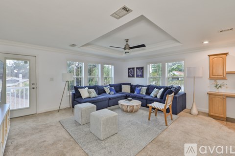 A living room with a blue couch and a white rug.