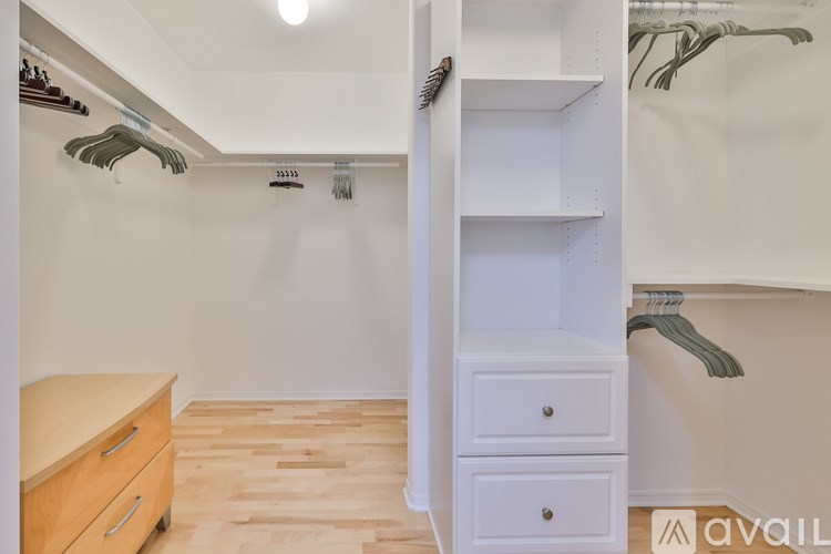 A white closet with a wooden floor and a white wardrobe with a hanger on top.