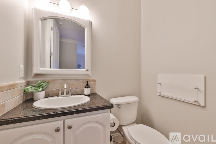 A bathroom with a sink, toilet, mirror, and towel rack.
