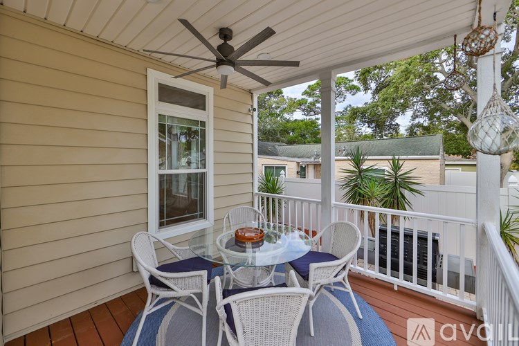 A patio with a table and chairs and a ceiling fan.