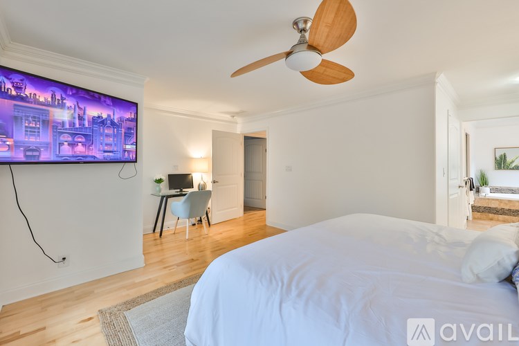 A bedroom with a large bed and a flat screen TV mounted on the wall.