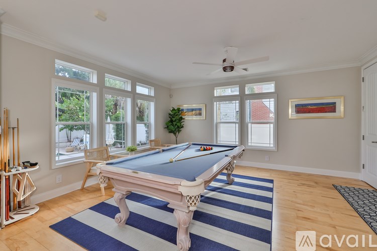 A pool table in a room with a ceiling fan and a striped rug.