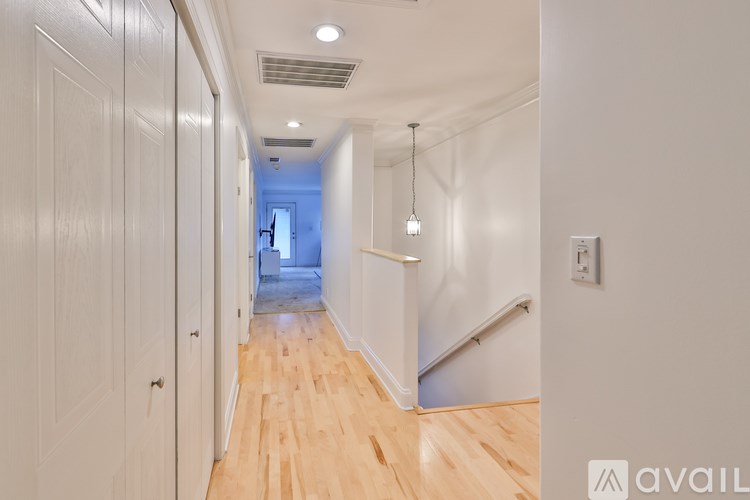 A hallway with wooden floors and white walls.