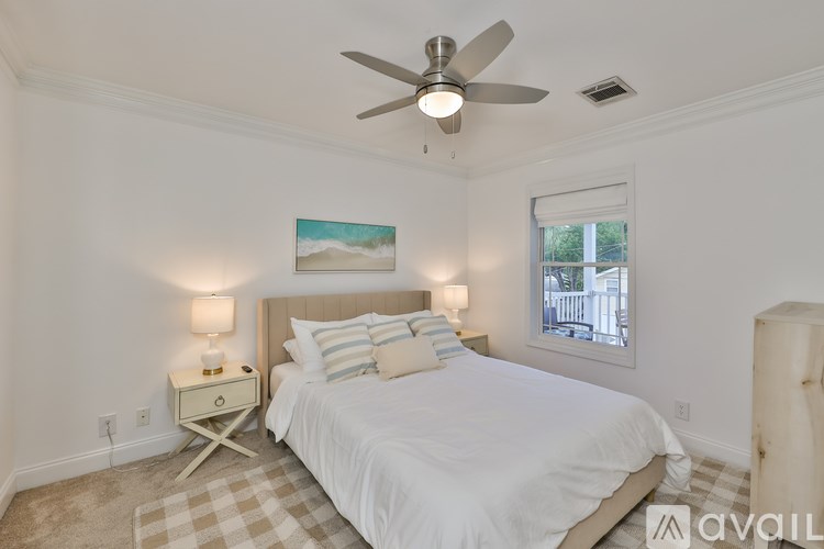 A bedroom with a bed, nightstand, and a painting of a beach scene on the wall.