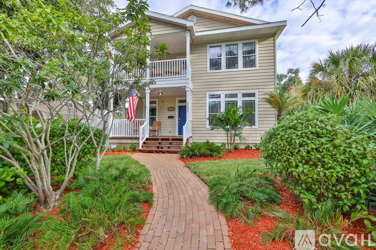 A house with a flag on the porch and a brick pathway leading to the front door.