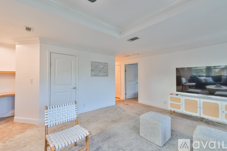 A living room with a white chair and a grey ottoman.