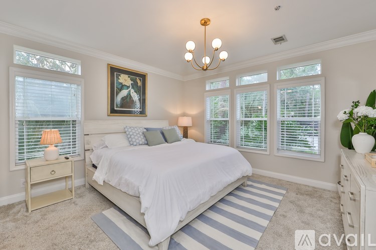 A bedroom with a large bed, a nightstand with a lamp, and a painting on the wall.