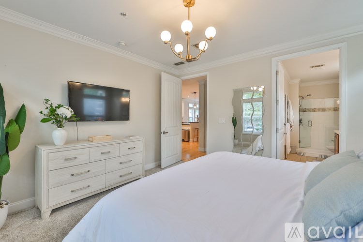 A bedroom with a large bed, a chandelier, and a television on the wall.