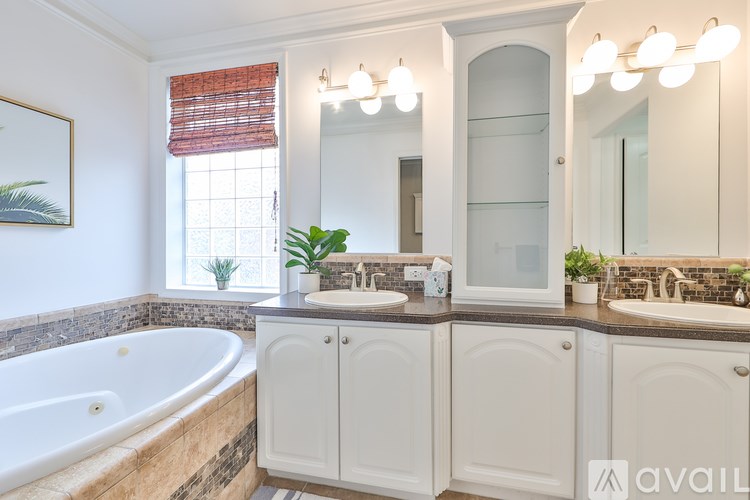 A bathroom with a tub, sink, and mirror.