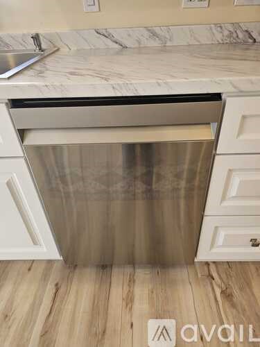 A kitchen with a stainless steel dishwasher and white cabinets.
