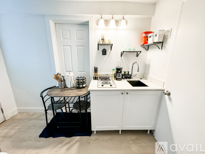A small kitchen with a white cabinet and a black chair.