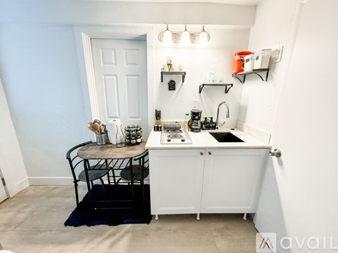 A small kitchen with a white cabinet and a black chair.