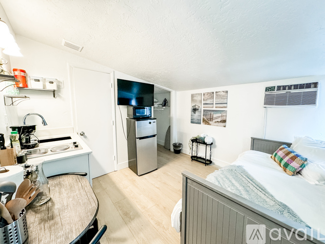 A kitchen area with a refrigerator, sink, and a bed in the same room.